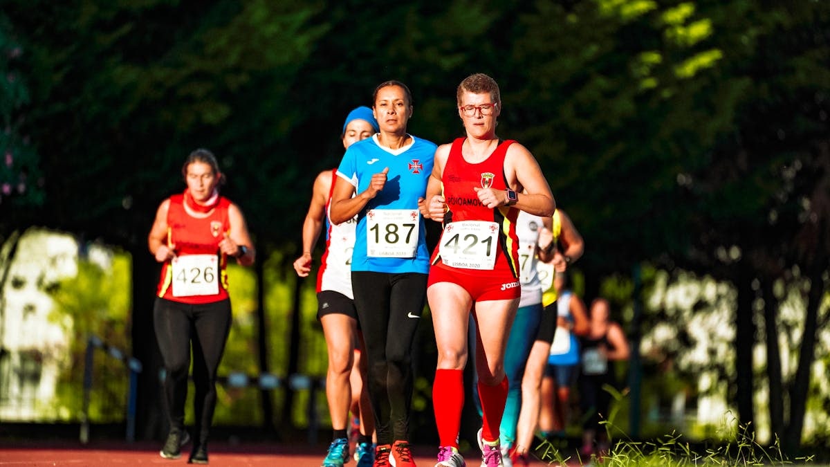 Group of sportswomen in active wear running while participating in track and field competition in stadium